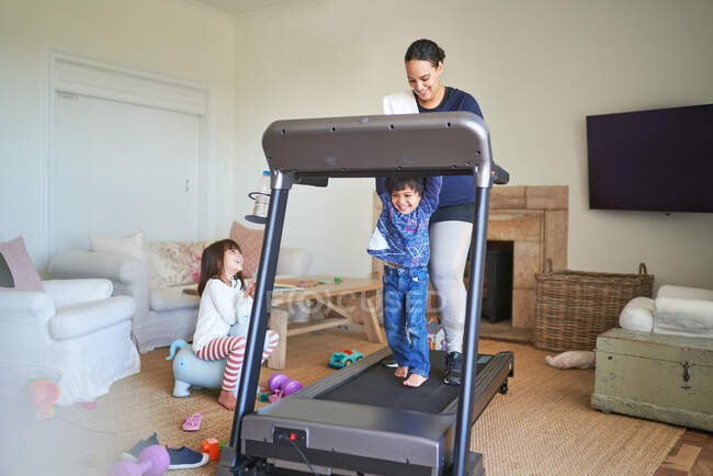 Mother and son walking on treadmill in living room — Stock Photo