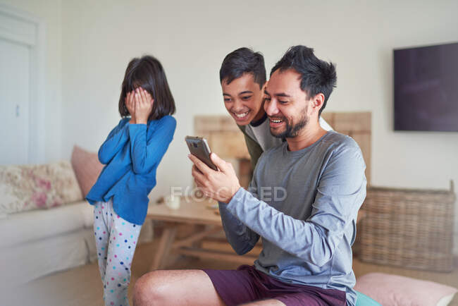 Padre e hijos usando un teléfono inteligente en la sala de estar - foto de stock