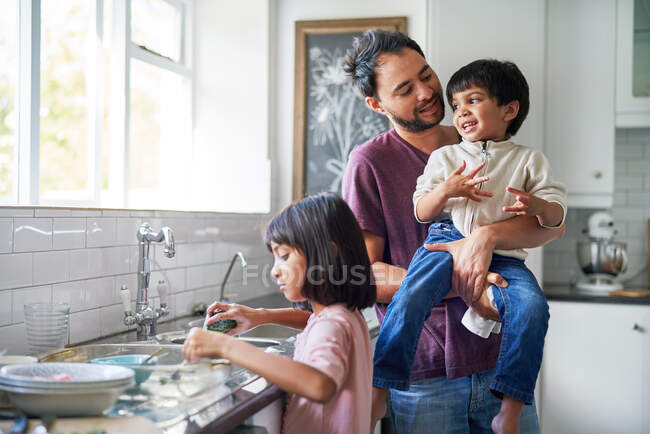 Pai feliz e crianças fazendo pratos na pia da cozinha — Fotografia de Stock