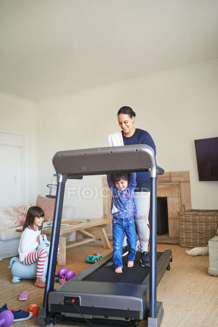 Madre e figlio che camminano sul tapis roulant in soggiorno — Foto stock