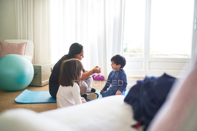 Madre e bambini che si esercitano sul tappetino da yoga in soggiorno — Foto stock