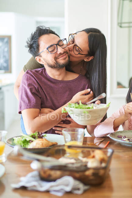 Cariñosa pareja besándose en cena mesa - foto de stock