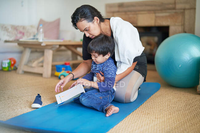 Madre e hijo en esterilla de yoga en la sala de estar - foto de stock