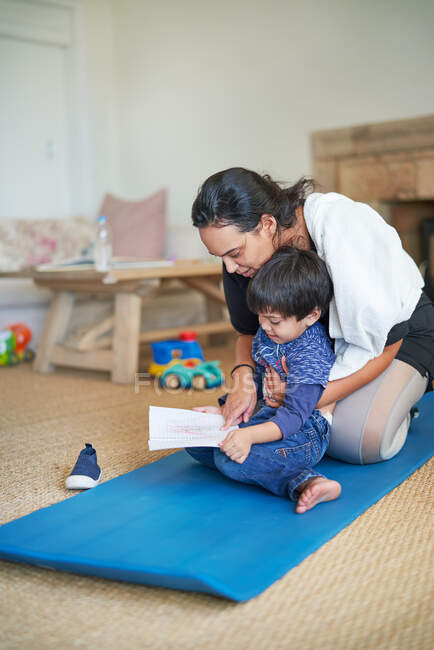 Сын показывает рисунок матери на коврике для йоги — стоковое фото