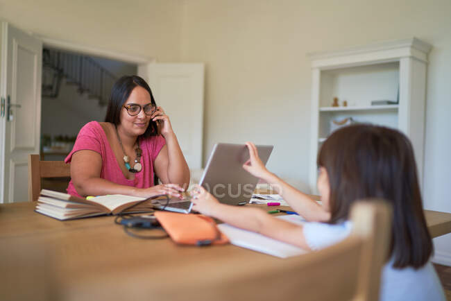 Filha distraindo mãe trabalhando no laptop na sala de jantar — Fotografia de Stock