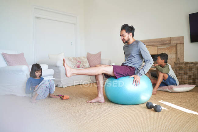 Father exercising in living room with kids — Stock Photo