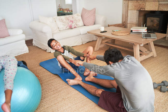 Грайливий батько і син вправляється на йога килимок у вітальні — стокове фото