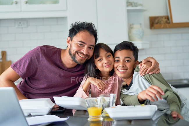 Retrato pai feliz e crianças comendo comida takeout na cozinha — Fotografia de Stock