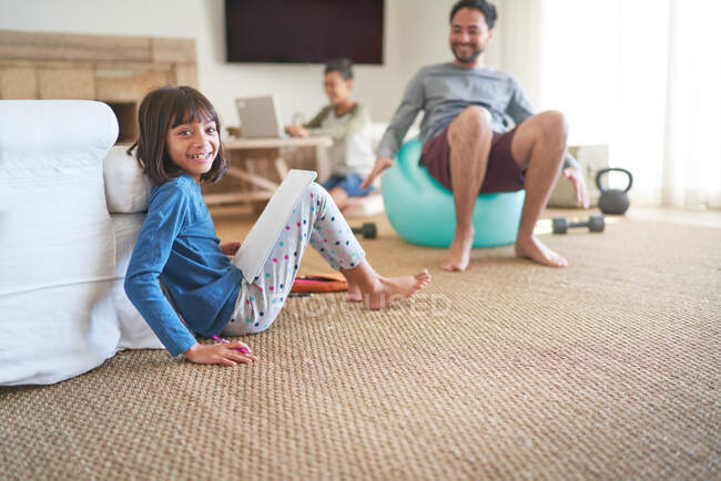 Retrato menina feliz fazendo lição de casa na sala de estar com a família — Fotografia de Stock