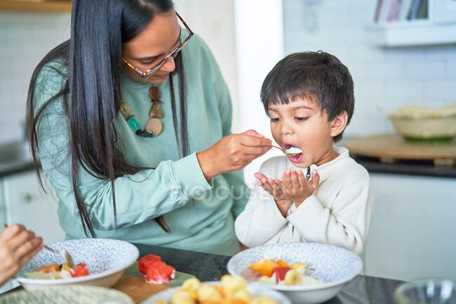 Mutter füttert Sohn in Küche — Stockfoto