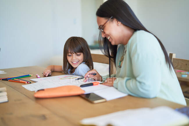 Mother helping daughter with homework at table — Stock Photo