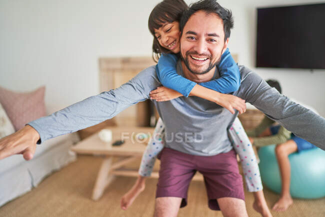 Retrato juguetón padre piggybacking hija - foto de stock