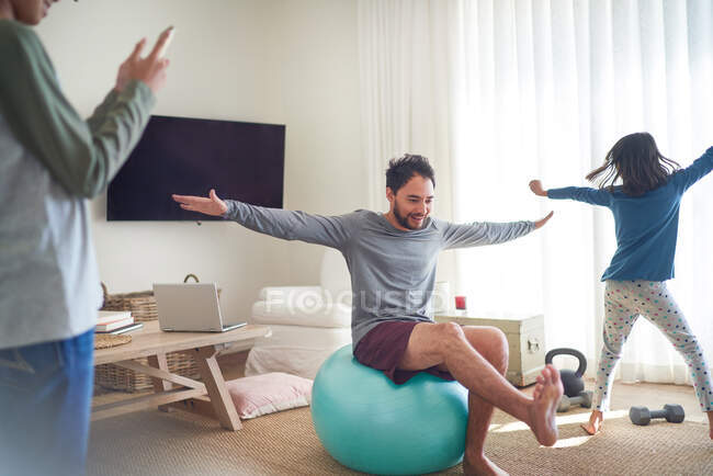 Padre e hijos haciendo ejercicio y jugando en la sala de estar - foto de stock
