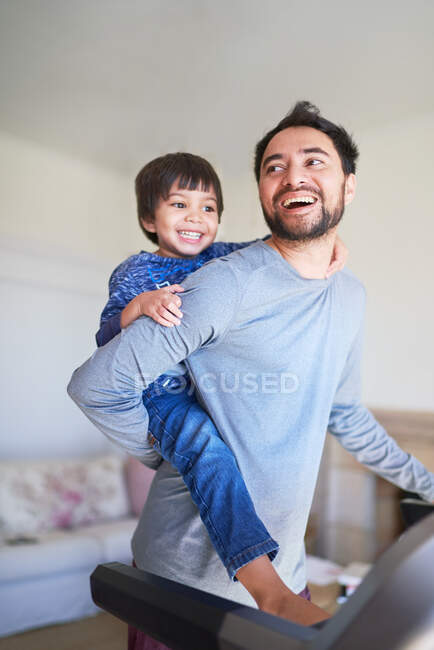 Heureux père piggybackking fils sur tapis roulant — Photo de stock