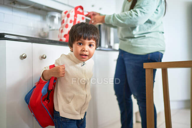 Retrato bonito menino com mochila na cozinha — Fotografia de Stock