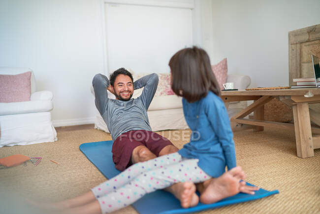 Padre e hija juguetones haciendo ejercicio en la sala de estar - foto de stock