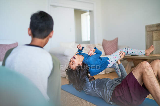 Brincalhão pai levantando filha e exercendo na sala de estar — Fotografia de Stock