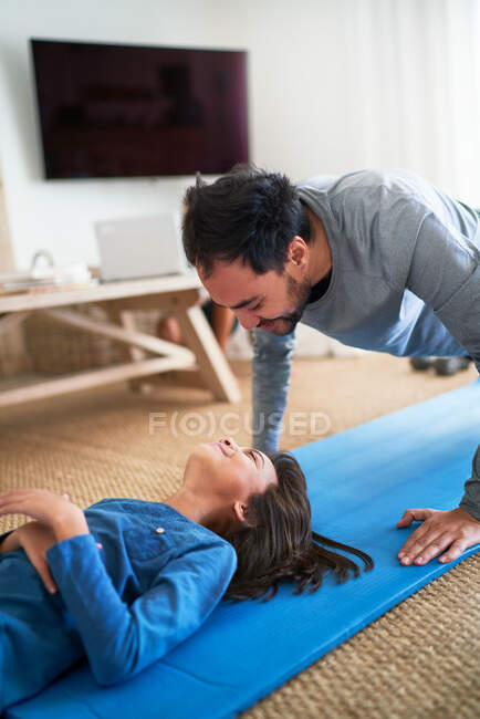 Verspielter Vater und Tochter beim Turnen im Wohnzimmer — Stockfoto