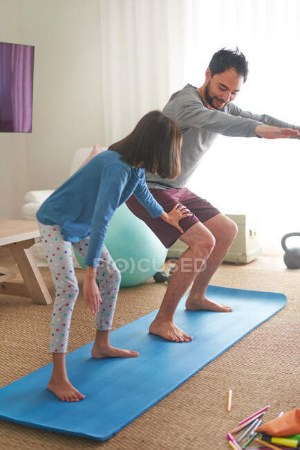 Отец и дочь занимаются на коврике в гостиной — стоковое фото