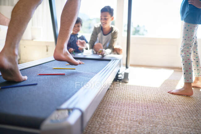 Kids throwing colored pencils on treadmill with father jogging — Stock Photo