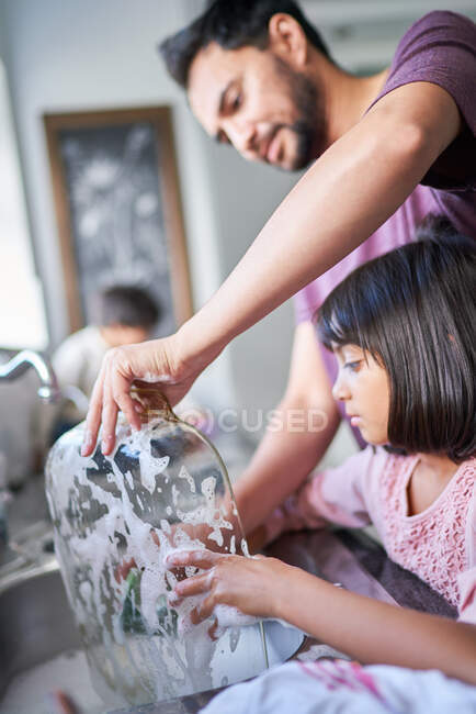 Father and daughter washing dishes at kitchen sink — Stock Photo