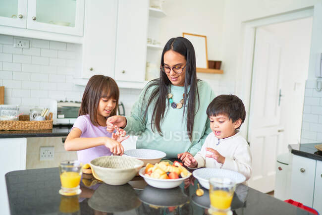 Mother and kids preparing fruit in kitchen — Stock Photo