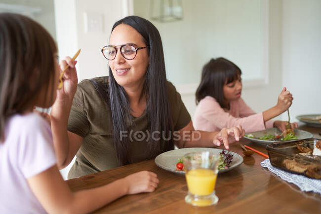 Mother feeding daughter at dinner table — Stock Photo