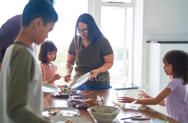 Family clearing food and dishes from lunch table — Stock Photo