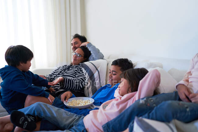 Familie entspannt sich und isst Popcorn auf Wohnzimmersofa — Stockfoto