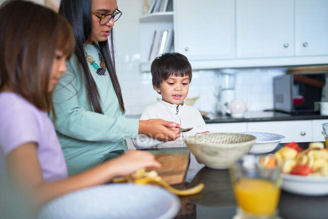 Mutter und Kinder schneiden frisches Obst in Küche — Stockfoto