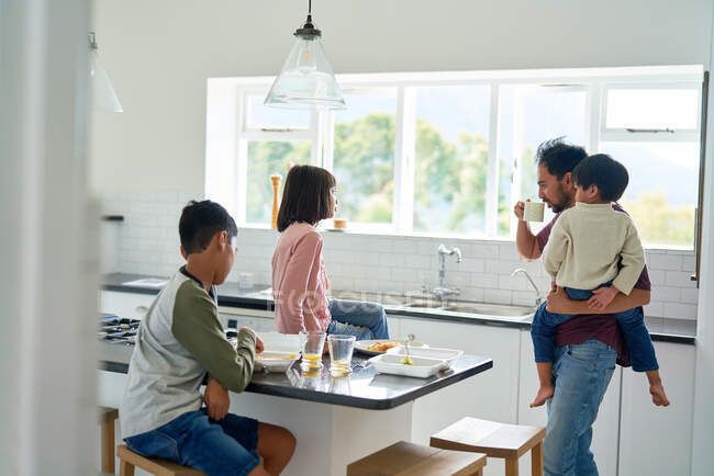 Pai e crianças comendo comida de comida na cozinha — Fotografia de Stock