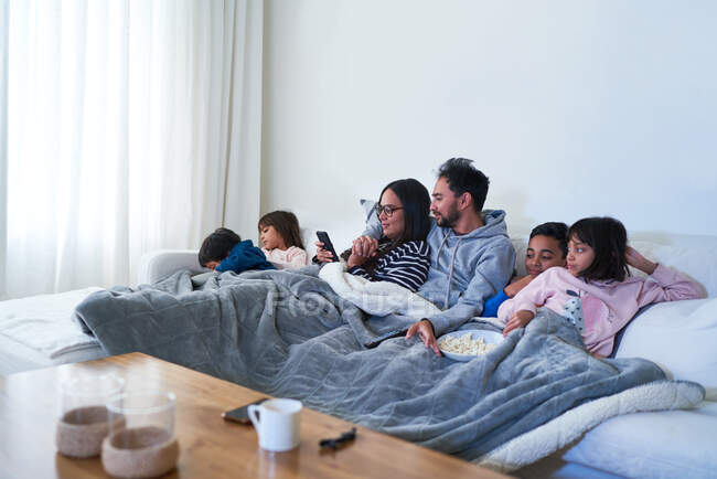 Familia relajante y ver películas en el sofá de la sala de estar - foto de stock