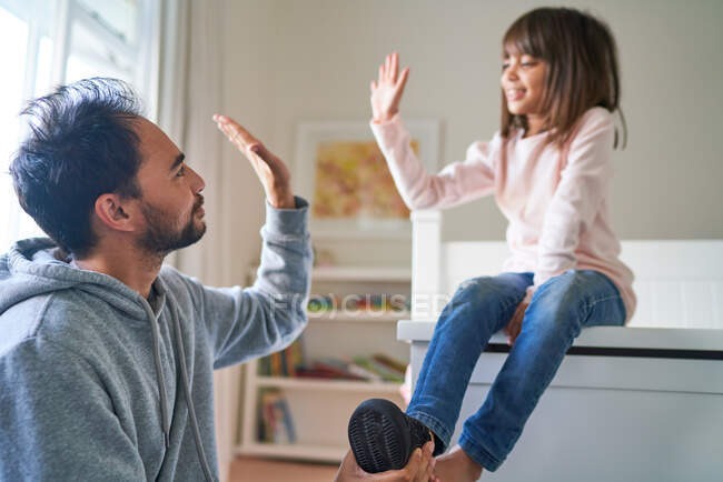 Father and daughter high-fiving in bedroom — Stock Photo