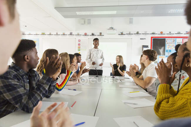 Estudiantes de secundaria aplaudiendo a su compañero de clase en clase de debate - foto de stock