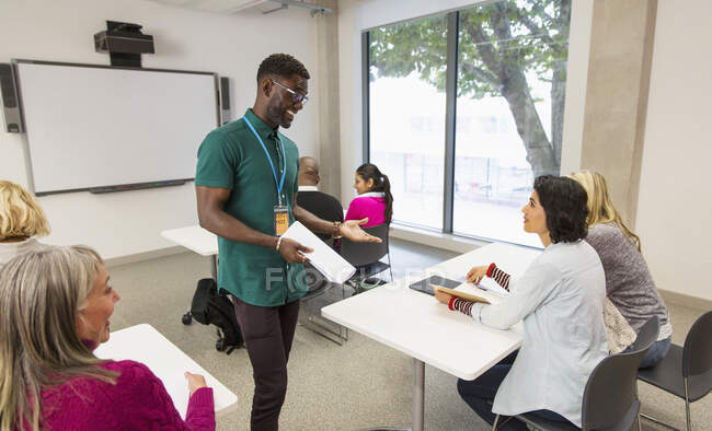 Instructor de la universidad comunitaria hablando con estudiantes en el aula - foto de stock