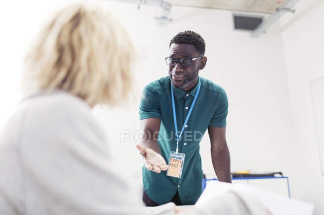 Male community college instructor talking with student in classroom — Stock Photo