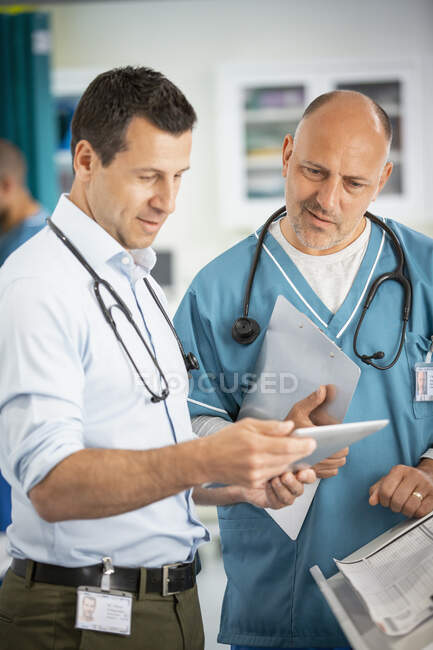 Male doctors consulting, using digital tablet in hospital — Stock Photo