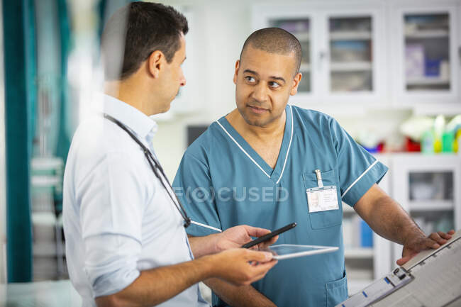 Médico y enfermera varones hablando en el hospital - foto de stock
