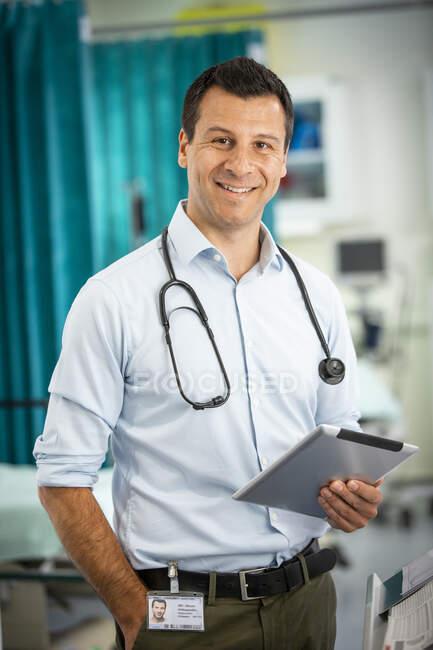 Портрет уверенный мужчина врач с цифровой таблеткой в больнице — стоковое фото
