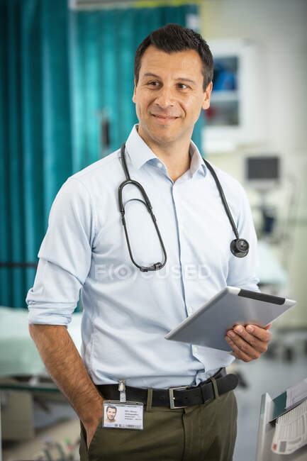 Портрет упевнений чоловік - лікар користується цифровою табличкою в лікарні. — стокове фото