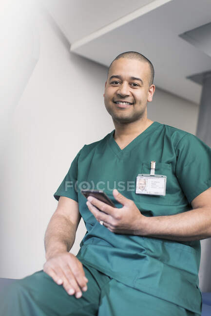 Retrato confiado cirujano masculino usando teléfono inteligente - foto de stock