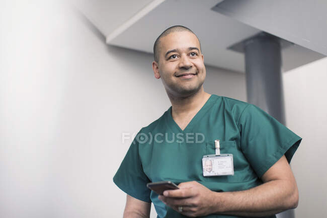 Улыбающийся хирург с помощью смартфона — стоковое фото