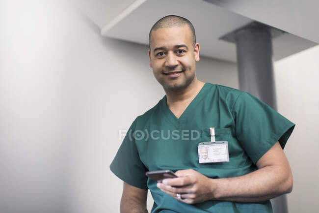 Portrait confiant, sourire chirurgien masculin en utilisant un téléphone intelligent — Photo de stock