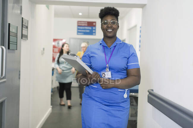 Портрет впевненої жінки-медсестри з медичною картою в лікарняному коридорі — стокове фото