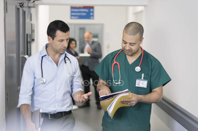 Médico y cirujano discutiendo historia clínica, haciendo rondas en el pasillo del hospital - foto de stock
