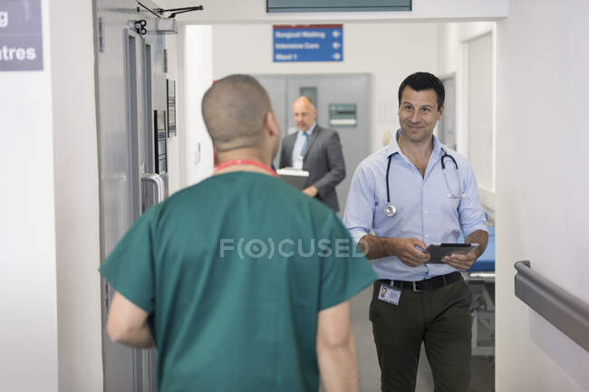 Los médicos masculinos saludan, pasando el uno al otro en el pasillo del hospital - foto de stock
