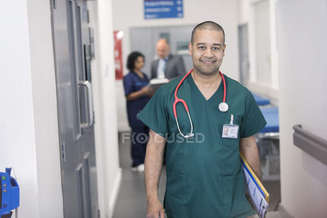Portrait confident male surgeon walking in hospital corridor — Stock Photo