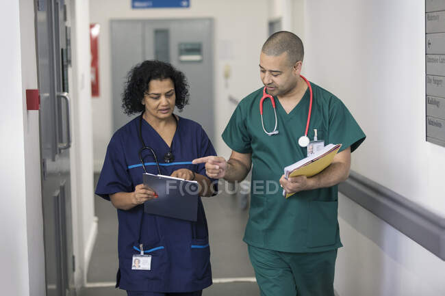 Médico e cirurgião discutindo prontuário, fazendo rondas no corredor do hospital — Fotografia de Stock