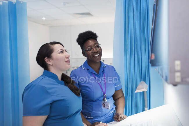 Female doctor and nurse examining x-rays in hospital room — Stock Photo