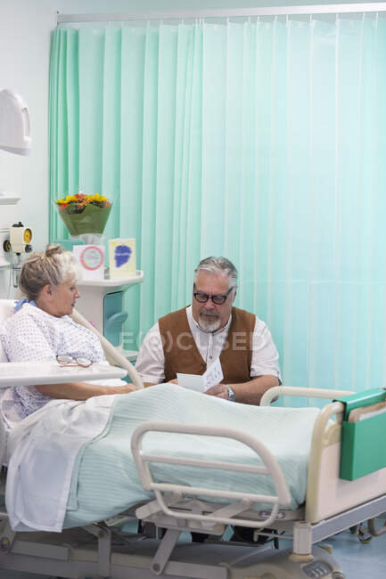 Uomo anziano con biglietto di auguri in visita moglie a riposo in camera d'ospedale — Foto stock